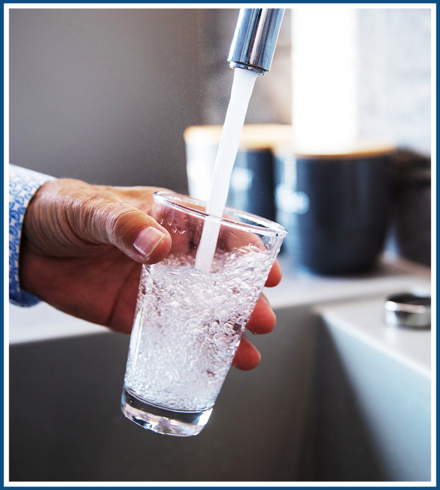 Clear glass filling with water under a kitchen faucet